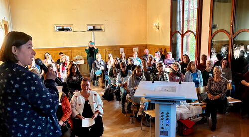 Blick in den Saal und in das Publikum. Vorn in der Mitte ein Rednerpult.